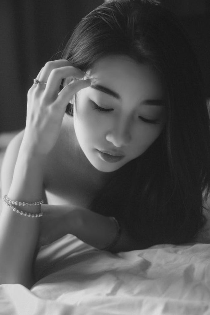 Elegant black and white portrait of a woman lying down with closed eyes, exuding tranquility.